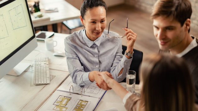 High angle view of Asian financial advisor handshaking with her clients on a meeting in the office.